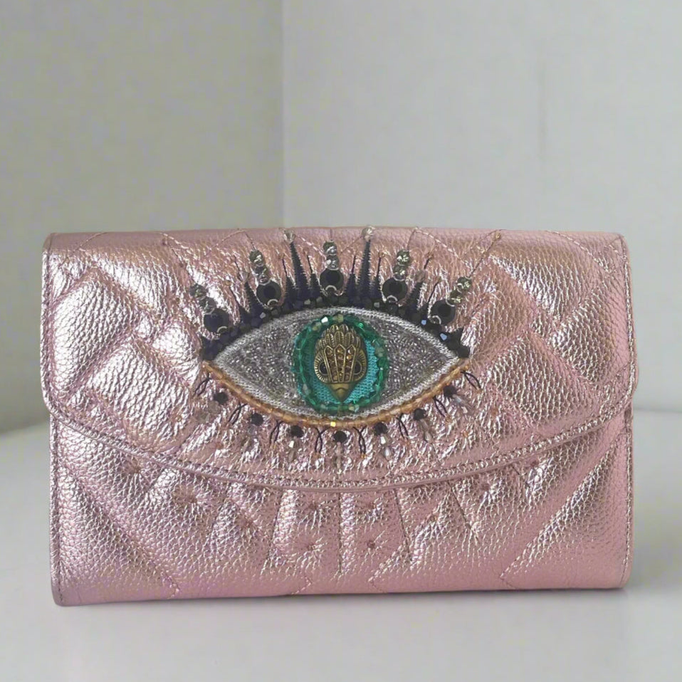 Pink wallet with eye design and embellishments on a white background