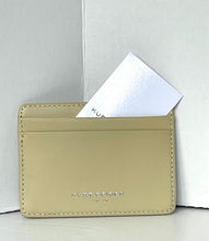 Load image into Gallery viewer, A light beige leather card holder wallet by Kurt Koho, featuring debossed branding and a white card partially inserted into the top slot, set against a light gray background.
