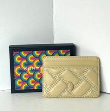 Load image into Gallery viewer, A beige quilted leather card holder wallet with a small embossed logo, displayed in front of its black packaging box which features a colorful rainbow pattern and the brand name 'KURT GEIGER'.