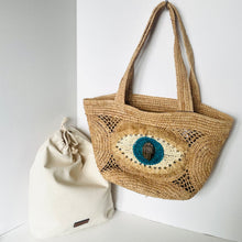 Load image into Gallery viewer, Woven bag with decorative eye design and a smaller drawstring bag on a light background