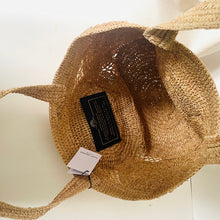 Load image into Gallery viewer, Woven straw bag with a tag on a light background