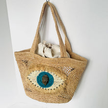 Load image into Gallery viewer, Woven bag with decorative eye design on a white background