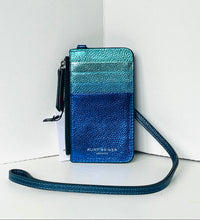 Load image into Gallery viewer, A metallic ombre blue phone wallet with a textured leather finish, featuring a black wristlet strap and a white hangtag, set against a white background.