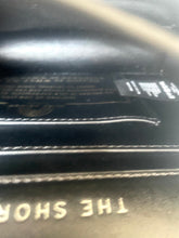 Load image into Gallery viewer, Close-up of a black leather product with 'The Shop' branding.