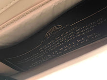 Load image into Gallery viewer, Close-up of a textured black surface with embossed text and design.