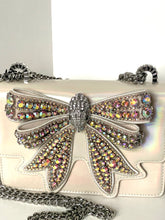 Load image into Gallery viewer, White handbag with a large, ornate bow made of multicolored crystals on a white background.