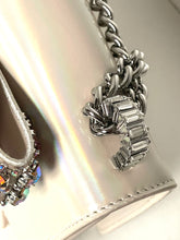 Load image into Gallery viewer, Close-up of a silver chain and crystal pendant on a white shoe.