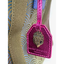 Load image into Gallery viewer, Pink luggage tag with a decorative emblem attached to a suitcase.