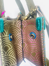 Load image into Gallery viewer, Close-up of a patterned bag with turquoise handles and metal hardware.