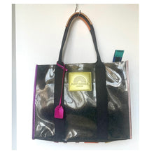 Load image into Gallery viewer, Transparent tote bag with black handles and a gold tag on a white background