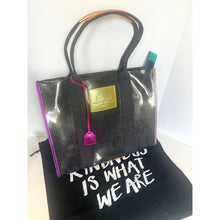 Load image into Gallery viewer, Black tote bag with a gold tag and pink handle on a white background