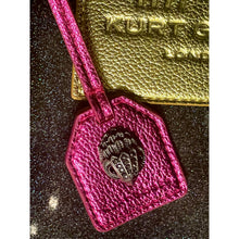 Load image into Gallery viewer, Pink leather luggage tag with a metal emblem on a dark textured surface
