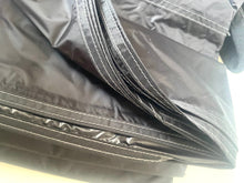 Load image into Gallery viewer, Close-up of a black waterproof fabric item, showing layered panels with white contrast stitching and a small black strap or loop at the top right.