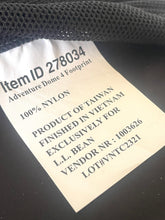 Load image into Gallery viewer, Close-up of a sewn-on fabric label reading 'Item ID 278034 Adventure Dome 4 Footprint 100% NYLON' attached to a dark mesh garment.