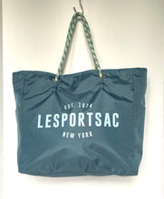 Load image into Gallery viewer, A dark teal blue nylon tote bag with green and white patterned rope handles, featuring the brand name 'LESportsac' printed in white on the front, hanging against a plain white wall.