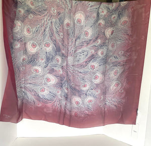 Silk scarf with peacock feather pattern on a white surface