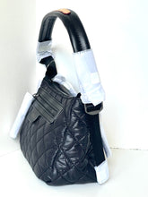 Load image into Gallery viewer, Black quilted handbag with a white protective cover on a light gray background