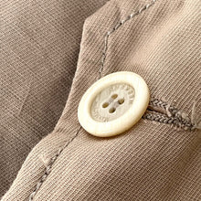 Load image into Gallery viewer, Close-up of a beige button on a textured fabric background