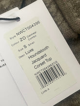 Load image into Gallery viewer, Clothing tag with product details on a textured surface