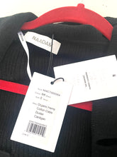 Load image into Gallery viewer, A close-up of a black knit sweater on a red hanger, showing a white NAADAM brand neck label and two white product tags with barcode details.
