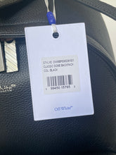 Load image into Gallery viewer, Clothing tag on a black leather surface with visible branding.