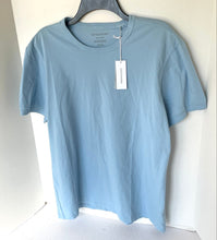 Load image into Gallery viewer, Light blue t-shirt on a hanger with a visible tag against a white background