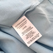 Load image into Gallery viewer, Fabric label on a light blue fabric with visible brand name and product details.