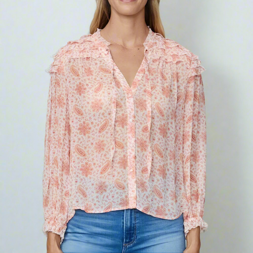 A woman wearing a pink paisley print long sleeve silk georgette blouse with a V-neck and ruffled trim, paired with blue jeans.