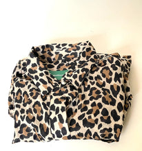 Load image into Gallery viewer, A folded leopard print button-up shirt with a beige base, brown and black spots, and a small green brand label reading 'SHUDUMY'.