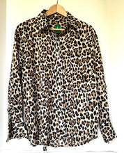 Load image into Gallery viewer, A leopard print long-sleeve button-up shirt hanging on a wooden hanger against a plain off-white wall.