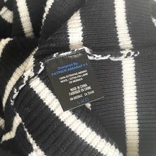 Load image into Gallery viewer, Textile label on a black and white striped fabric with 'Patrick Assara' branding.