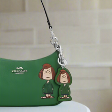 Load image into Gallery viewer, Green Coach handbag with a Peanuts character charm on a white background