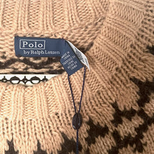Load image into Gallery viewer, Close-up of a Polo by Ralph Lauren label on a knitted sweater with a patterned background.