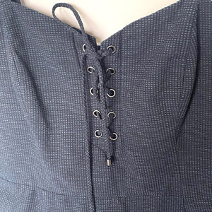 Textured gray garment with lace-up front on a neutral background