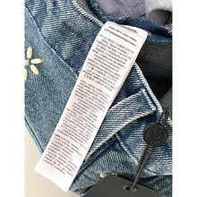 Load image into Gallery viewer, Close-up of a denim jacket with a tag displaying text details.