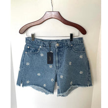 Load image into Gallery viewer, Blue denim shorts with floral embroidery on a hanger against a white background