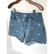 Load image into Gallery viewer, Blue denim shorts with white floral patterns on a hanger against a white background