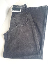 Load image into Gallery viewer, A pair of folded dark gray denim jeans with a visible back pocket and a black brand label at the waistband, photographed on a plain white background.