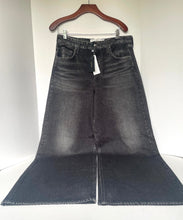 Load image into Gallery viewer, A pair of dark gray washed denim flare jeans hanging on a wooden hanger against a plain white wall.