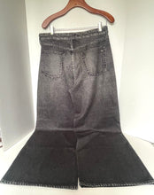 Load image into Gallery viewer, A pair of faded black denim flare jeans hanging on a wooden hanger against a white background.
