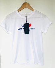 Load image into Gallery viewer, A white short-sleeve crewneck t-shirt hanging on a wooden hanger against a plain white wall. The shirt features a graphic print on the chest reading 'I <heart> NEW YORK CITY' in blue text with a red heart.