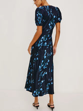 Load image into Gallery viewer, A woman modeling a navy midi dress with a light blue floral pattern, shown from the back against a plain white studio background.