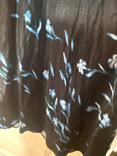 Load image into Gallery viewer, A close-up of a black fabric garment, likely a skirt or dress, featuring a light blue floral and leaf pattern.