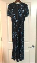 Load image into Gallery viewer, A black short-sleeve maxi dress with a blue floral pattern, hanging on a wooden hanger on a white paneled door.