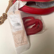 Load image into Gallery viewer, Red belt and beige bottle in a clear plastic bag with a red bag in the background.