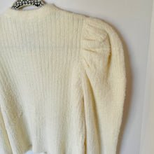 Load image into Gallery viewer, Cream-colored cardigan on a hanger against a white wall