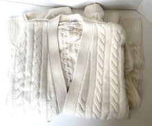 Load image into Gallery viewer, Stack of white cable knit sweaters on a white background