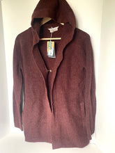 Load image into Gallery viewer, A ribbed knit hooded cardigan sweater in a deep burgundy or maroon color, hanging on a wooden hanger with tags attached against a plain white wall.