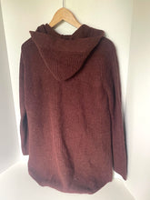 Load image into Gallery viewer, A ribbed knit hooded sweater in a deep burgundy or maroon color, hanging on a wooden hanger against a plain white wall.