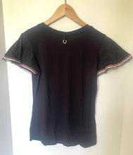 Load image into Gallery viewer, A black short-sleeve t-shirt with frayed trim on the sleeves, hanging on a wooden hanger against a plain white wall.